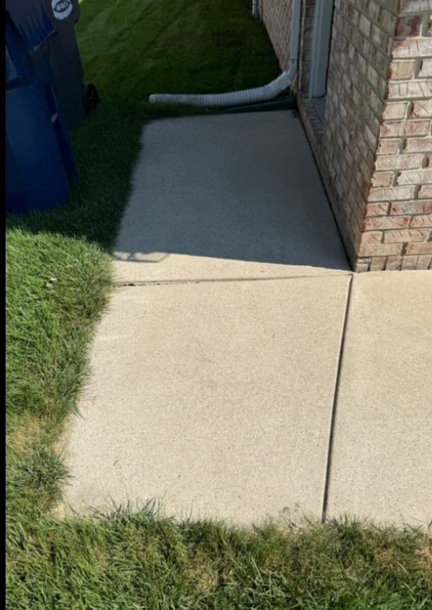 Same concrete sidewalk after pressure washing, fully restored